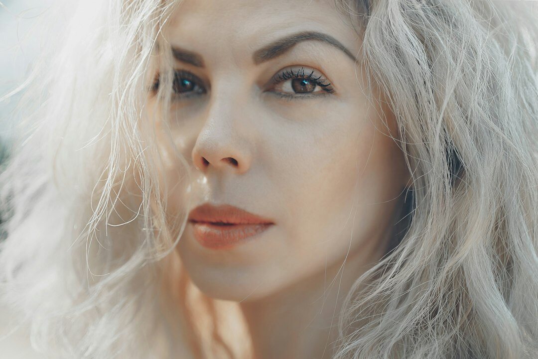 Studio portrait of a European woman in her 50s with silver hair wearing a scarf