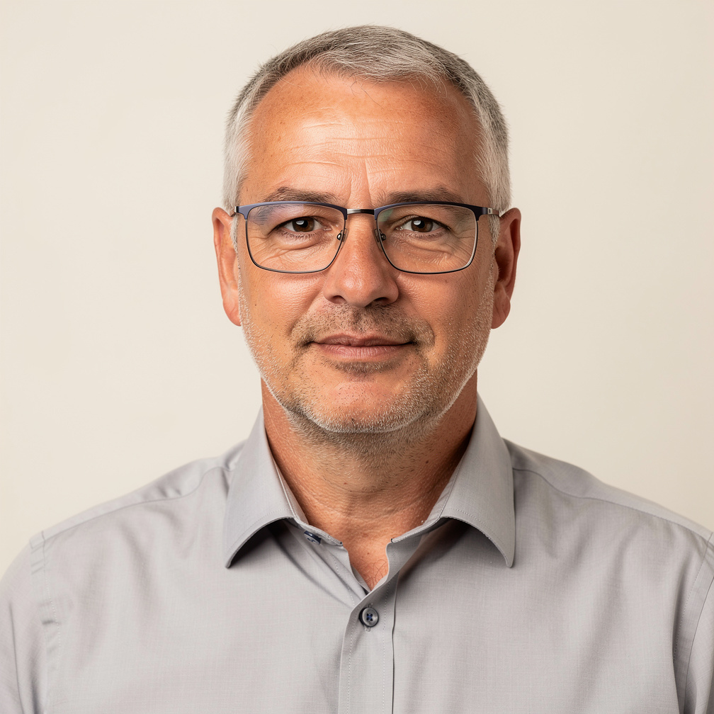 Studio portrait of a European man in his 50s with gray hair and glasses