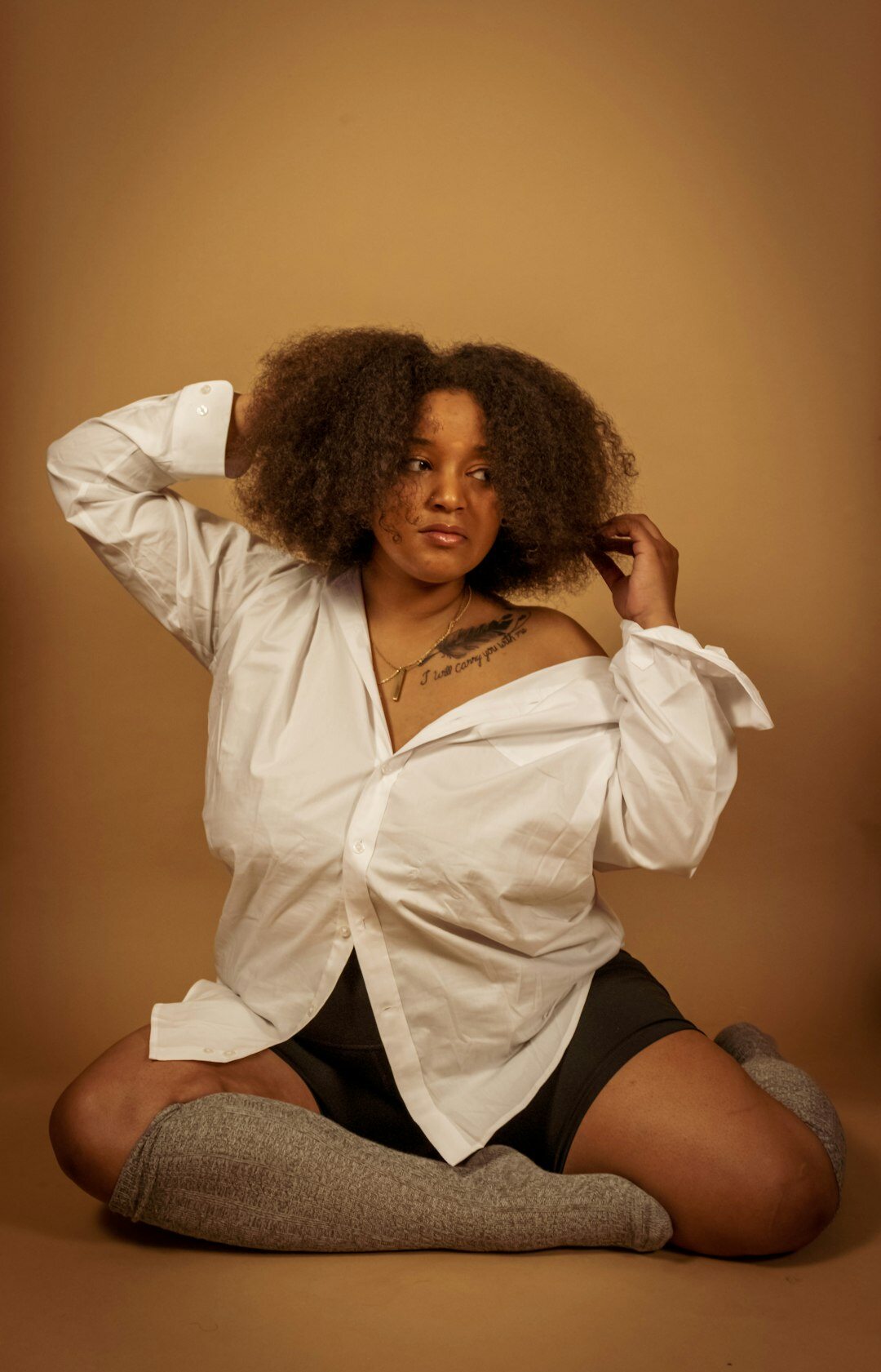 Studio portrait of a Black woman in her 30s with curly hair wearing a blouse